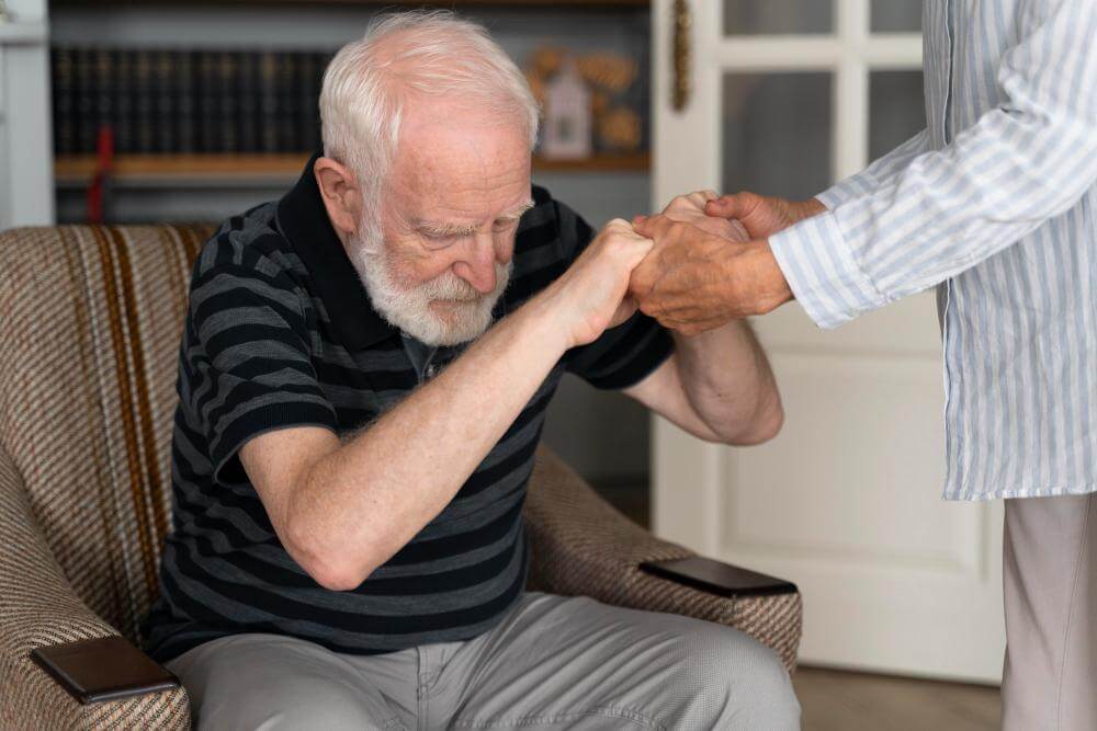De ziekte van Parkinson - oude man in een stoel wordt geholpen met opstaan. - Ik Wil Therapie -