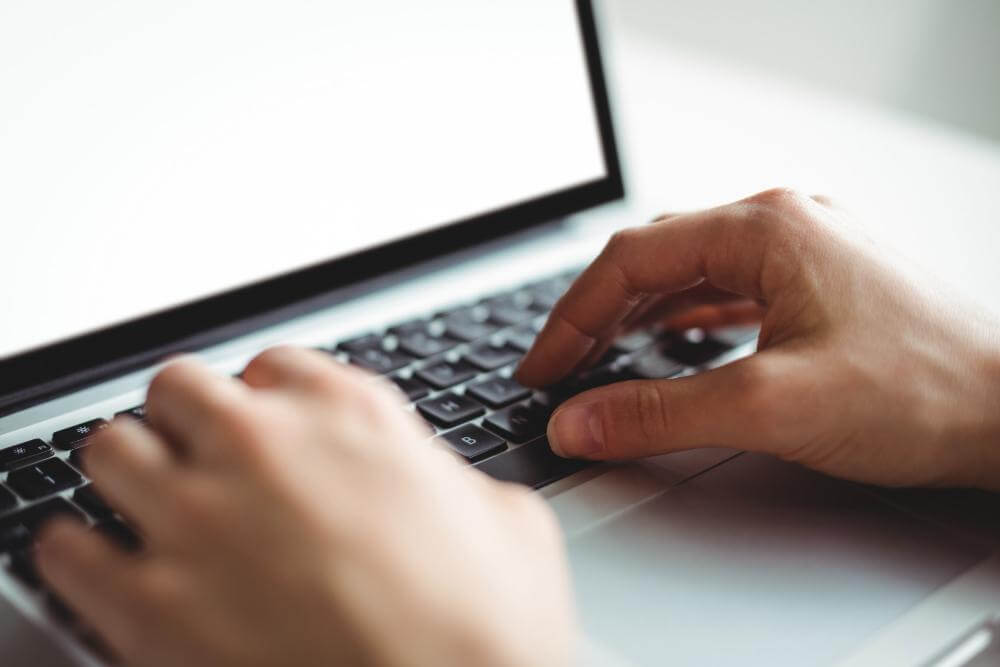 Hoe lang mag je werken achter een computer? Afbeelng van een persoon die aan het invoeren is op een laptop. - Ik Wil Therapie -