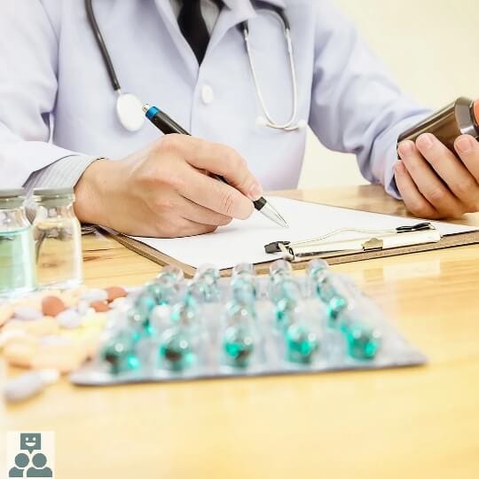 Arts schrijft medicijnen voor, op het bureau liggen medicijnen in verpakking.