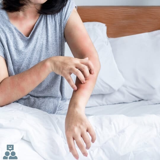 Bedwantsen, een vrouw zit rechtop in bed en is haar onderarm aan het krabben.