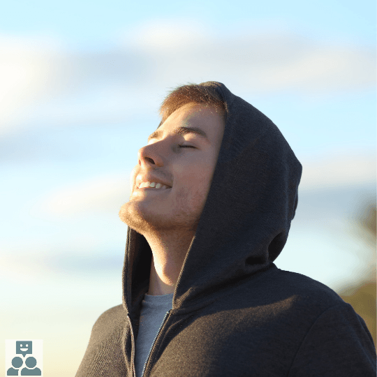 Wandelcoaching samen met Mindfulness, op de foto is een man afgebeeld met een zwarte hoodie en kijkt bevrijdend omhoog. De man is licht behaard op zijn gezicht